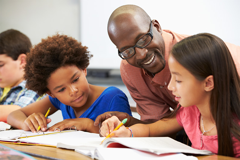 Male teacher helping young student with classwork